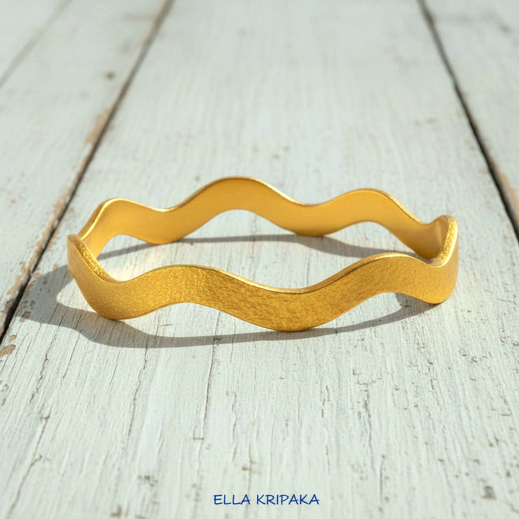 24k gold hammered bracelet bangle with wavy design on white rustic wooden background, branded 'Ella Kripaka'