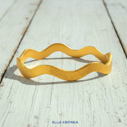 24k gold hammered bracelet bangle with wavy design on white rustic wooden background, branded 'Ella Kripaka'