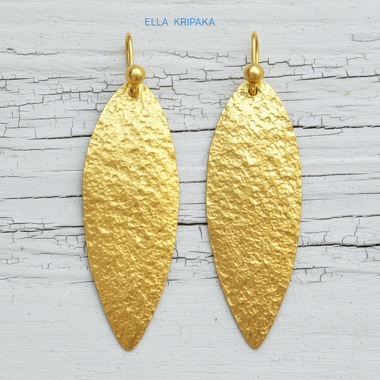 Hammered 24k Gold leaf textured earrings on a white old wooden background with 'Ella Kripaka' branding