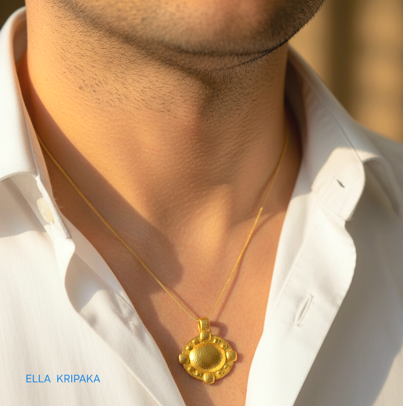Hammered 24k gold convex Byzantine pendant with chain worn by a man and with a white shirt background with 'Ella Kripaka' branding