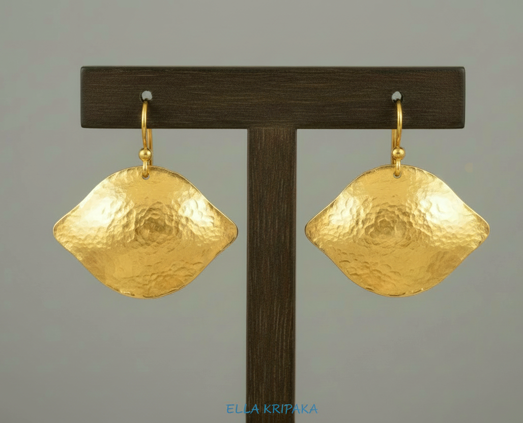 24k 9999 gold hammered Byzantine convex earrings with shiny gold textures are on dark wooden stand on grey background, artist-jeweler's name 'Ella Kripaka'