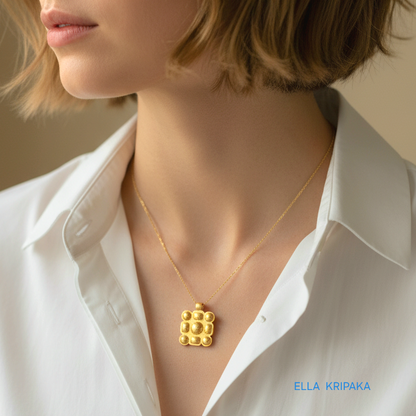Hammered 24k gold square pendant convex pattern with chain worn by a woman and with a white shirt and on grey background, with 'Ella Kripaka' branding