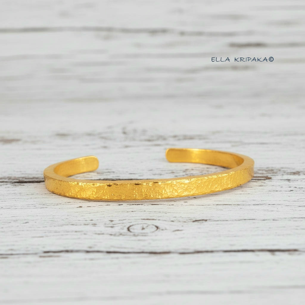 Hammered 24k 9999 gold cuff thick bracelet Ancient Rome style on an old white wooden background, artist-jeweler name 'Ella Kripaka' branding
