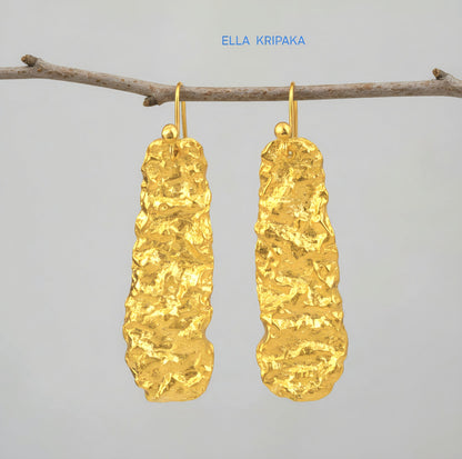 Organic hammered uneven 24k 9999 Gold earrings hanging on a branch and on a grey background, with 'ELLA KRIPAKA' branding