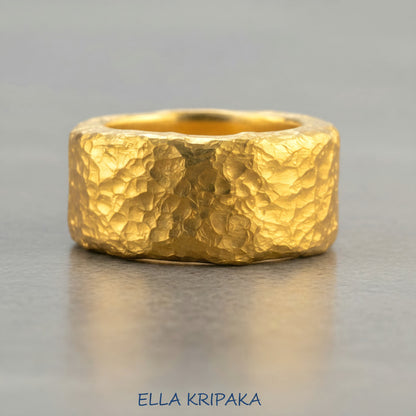 Hammered 24k 9999 Gold thick ring Ancient Rome style with textured gold on a grey concrete background, branded 'Ella Kripaka'