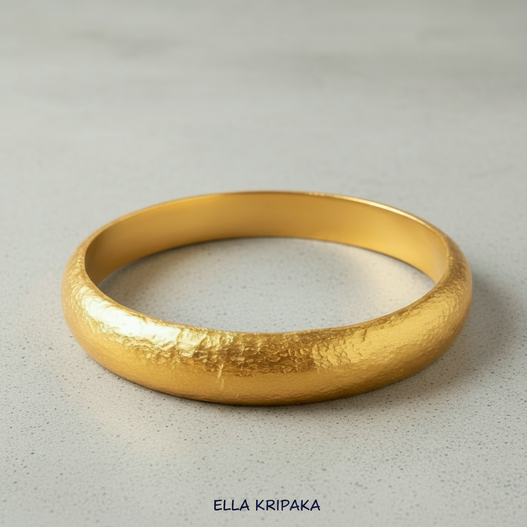 Hammered 24k gold bangle thick bracelet with rounded edges on grey concrete background, and artist-jeweler 'Ella Kripaka' branding
