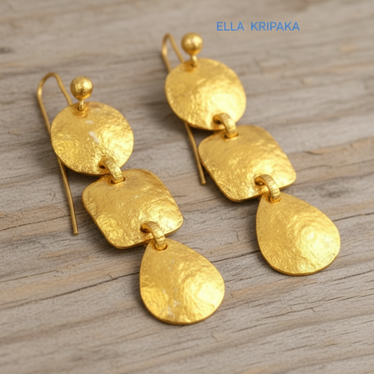 Solid 24k 9999 gold hammered Byzantine earrings with hook clasps and shiny forged gold textures on old wooden background , artist's name 'ELLA KRIPAKA'