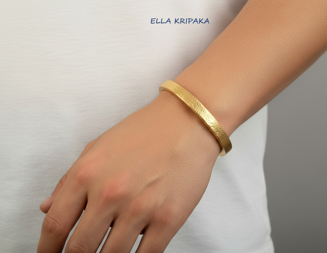 Hammered 24k 9999 gold cuff thick bracelet Ancient Rome style  worn by a man in white t-shirt and on grey background, artist-jeweler name 'Ella Kripaka' branding
