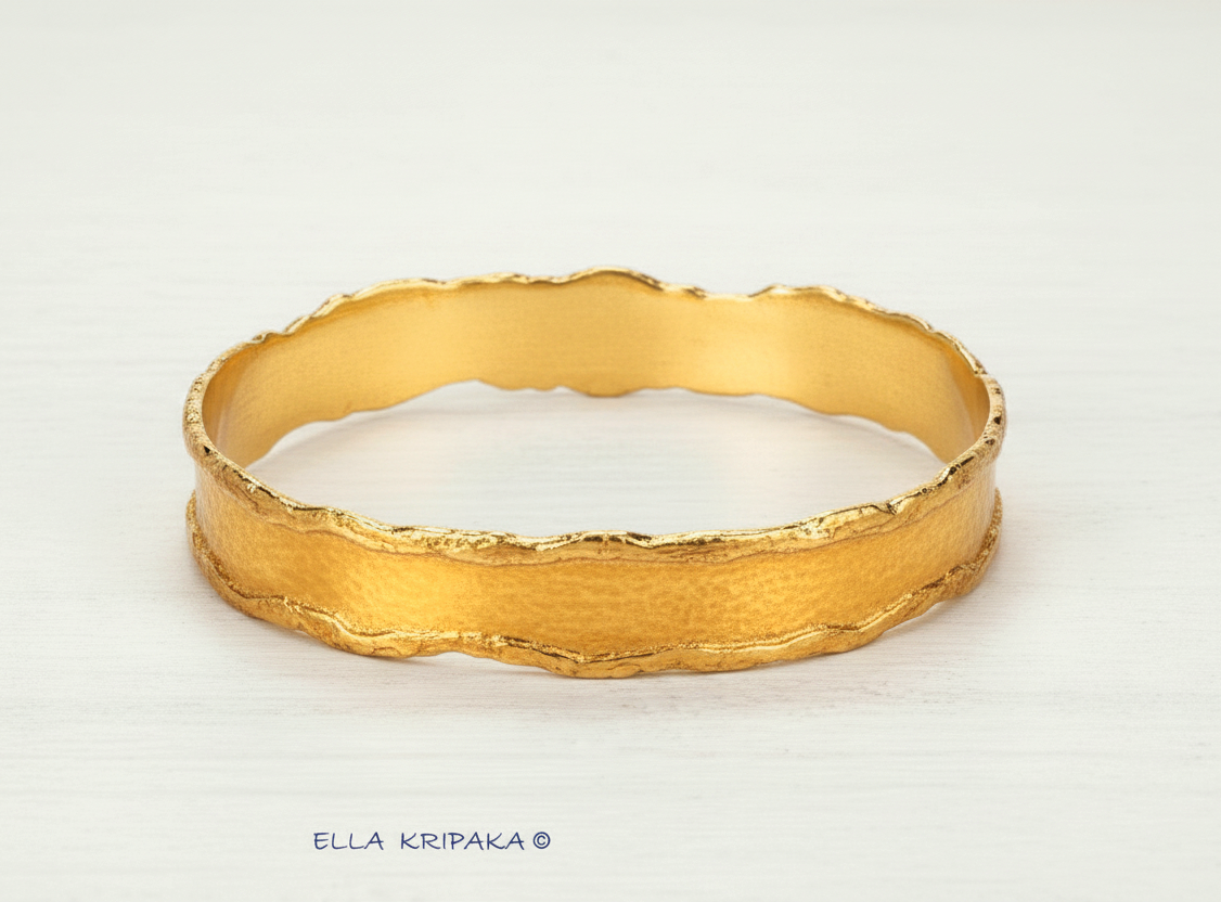 Organic Hammered 24k Gold Bangle Bracelet Textured with uneven thick edges on a white wooden surface, branding artist-jeweler 'Ella Kripaka'