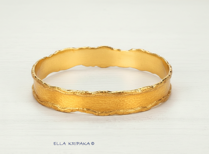 Organic Hammered 24k Gold Bangle Bracelet Textured with uneven thick edges on a white wooden surface, branding artist-jeweler 'Ella Kripaka'
