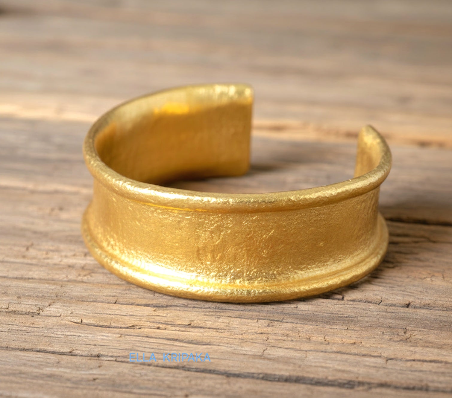 Hammered 24k 9999 gold bracelet cuff Ancient Rome style on old wooden surface with 'Ella Kripaka' branding