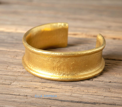 Hammered 24k 9999 gold bracelet cuff Ancient Rome style on old wooden surface with 'Ella Kripaka' branding