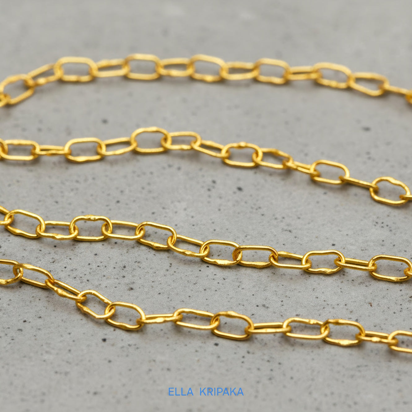 22k gold hammered chain necklace on grey concrete background, artist-jeweler's name 'Ella Kripaka' branding