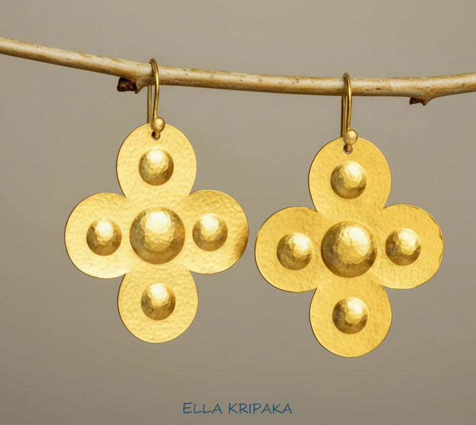 24k 9999 gold hammered Byzantine cross earrings with shiny gold textures are hanging on branch on grey background, artist-jeweler's name 'Ella Kripaka'