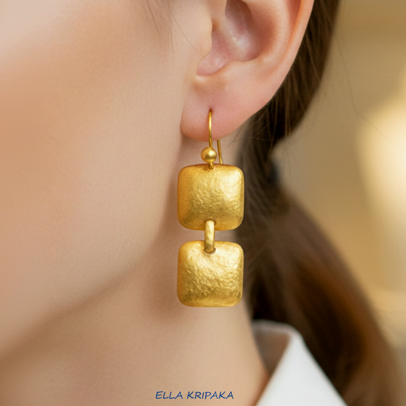 Solid 24k 9999 gold hammered Byzantine earrings with hook clasps and shiny forged gold textures worn by model and on neutral background , artist's name 'ELLA KRIPAKA'