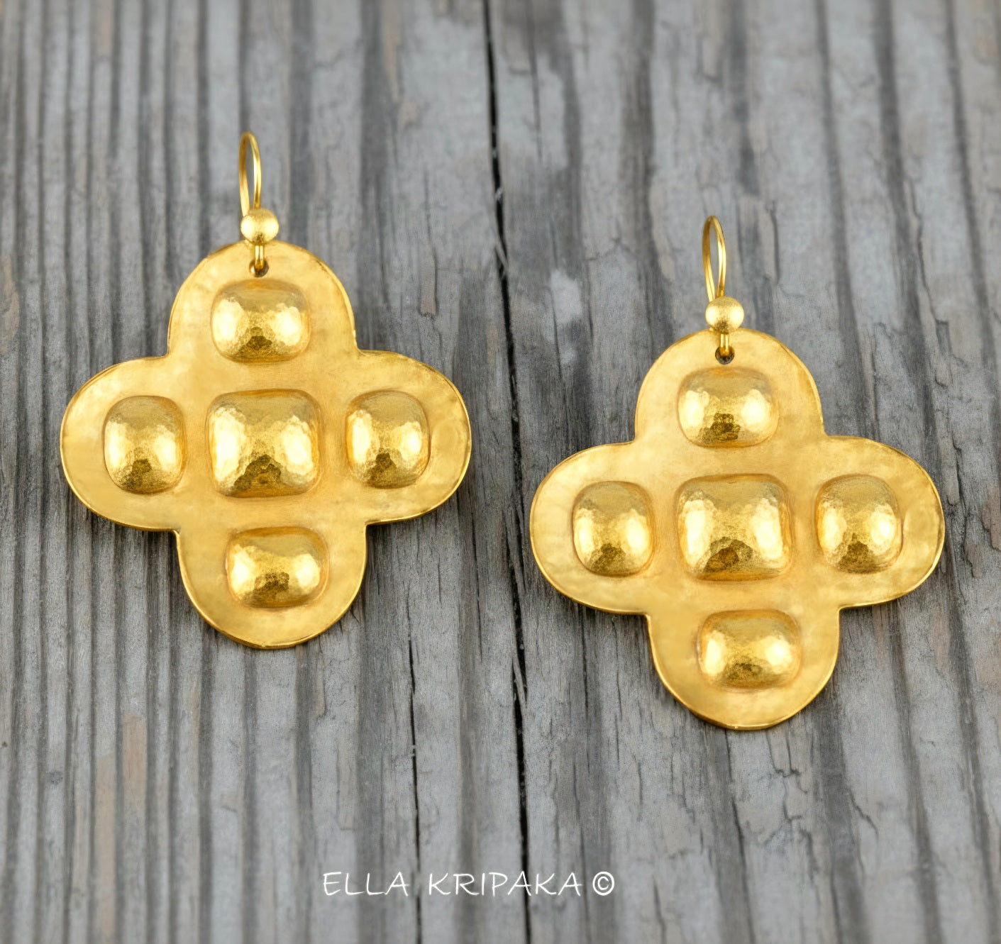 Hammered 24k 9999 Gold Byzantine cross earrings on a old wooden background with 'Ella Kripaka' branding