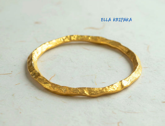 Organic hammered 24k 9999 Gold thick bangle uneven bracelet on neutral background, artist's name 'Ella Kripaka' branding
