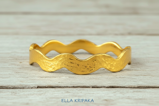 Wavy Hammered 24k 9999 Gold bangle bracelet on white wooden surface, artist's name 'Ella Kripaka' branding