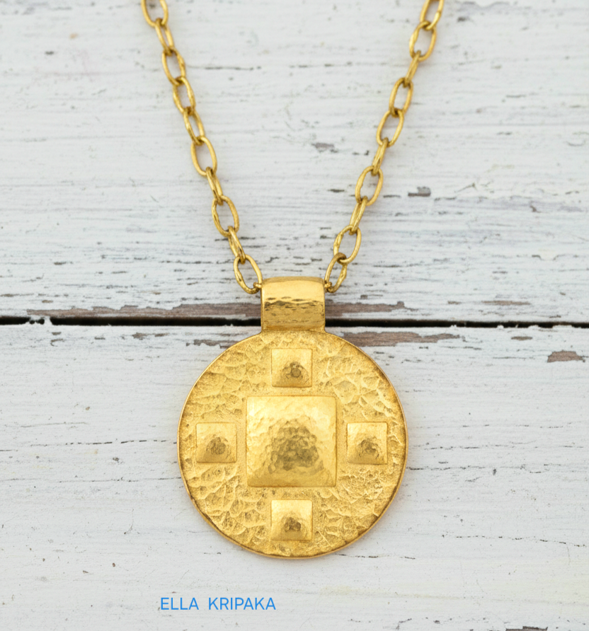 24k gold disk pendant textured hammered with convex pattern and with chain on white old wooden background, with 'Ella Kripaka' branding