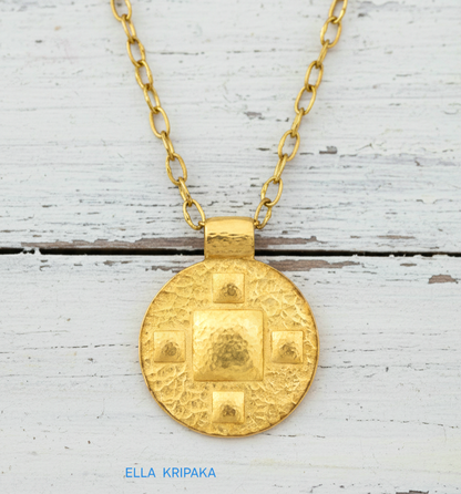 24k gold disk pendant textured hammered with convex pattern and with chain on white old wooden background, with 'Ella Kripaka' branding