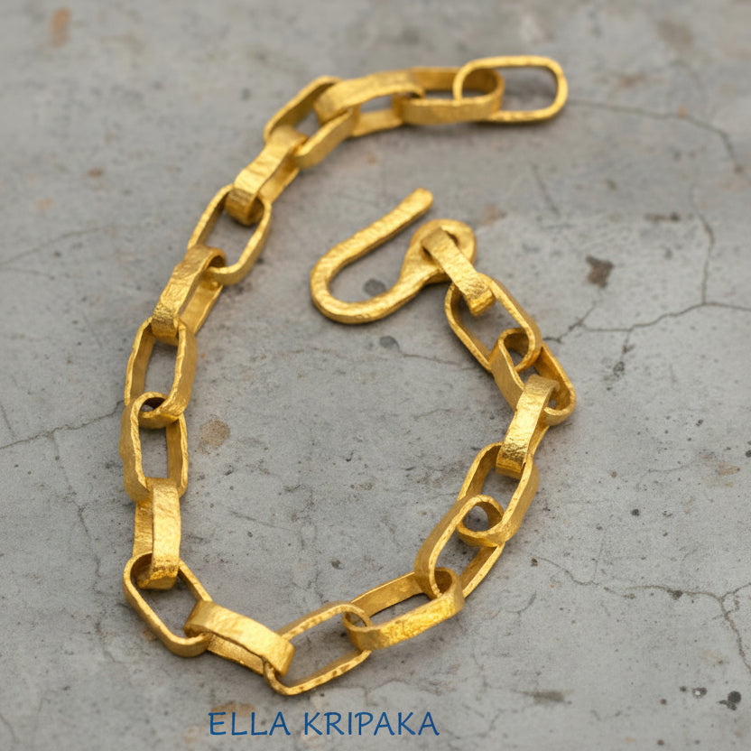 Hammered 24k 9999 gold chain thick bracelet with thick hook clasp Ancient Rome style on a old wooden background, artist-jeweler name 'Ella Kripaka' branding