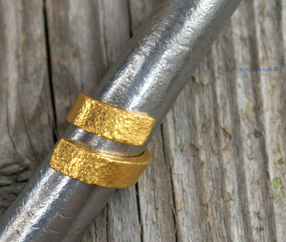 Hammered twisted 24k Gold 9999 gold signet thick ring with textured gold on a metallic ring mandrel jewelry tool on grey wooden background, branded 'Ella Kripaka'