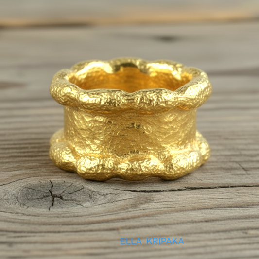 Hammered 24k 9999 Gold thick uneven wavy ring organic with a textured gold surface on a old wooden background, branded 'Ella Kripaka'