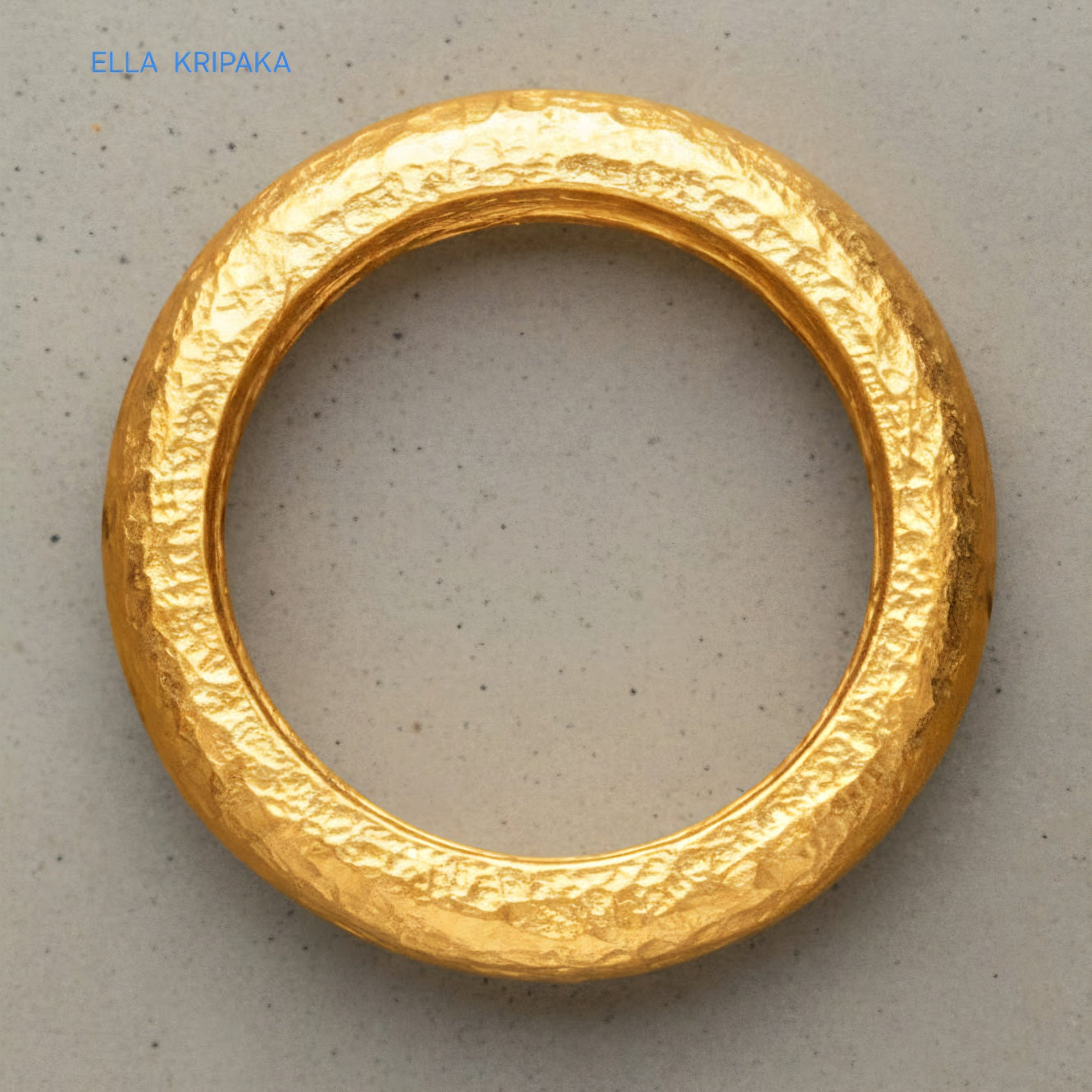 Hammered 24k Gold 9999 gold ring band thick heavy and with textured surface on a grey concrete background, branded 'Ella Kripaka'