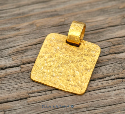 Hammered 24k gold, pure 9999 gold square pendant with shiny forged gold textures on old wooden surface, artist-jeweler 'Ella Kripaka' branding