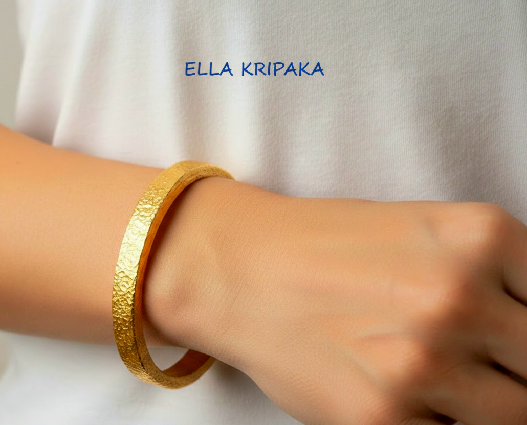 Hammered 24k 9999 gold bangle thick bracelet Ancient Rome style worn by a woman on hand and on a white t-shirt background, artist-jeweler name 'Ella Kripaka' branding