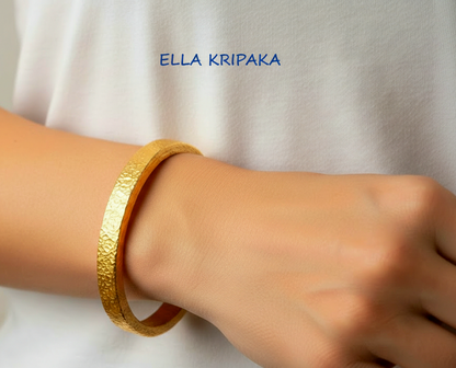 Hammered 24k 9999 gold bangle thick bracelet Ancient Rome style worn by a woman on hand and on a white t-shirt background, artist-jeweler name 'Ella Kripaka' branding