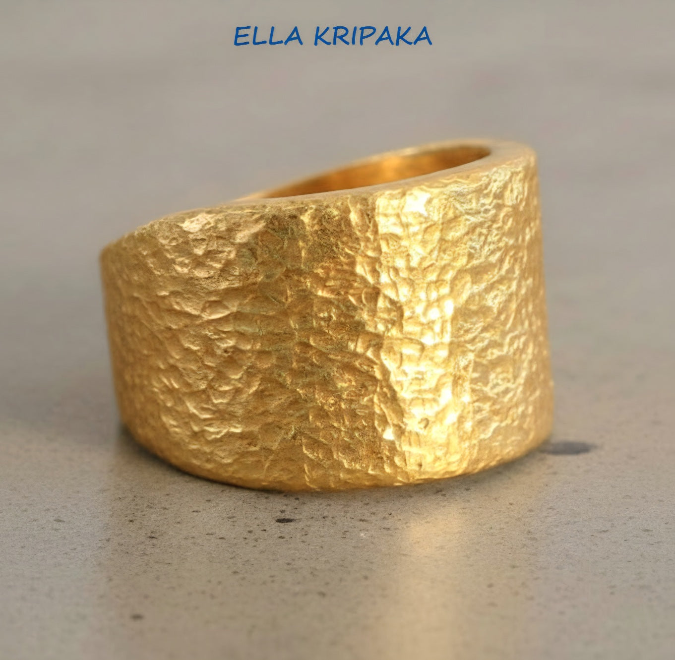 Hammered 24k Gold 9999 gold Ancient Rome  thick ring large signet with textured gold on a grey concrete background, branded 'Ella Kripaka'