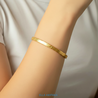 Hammered 24k gold bangle thick bracelet Ancient Rome 34g style worn by a person on hand and on a white t-shirt background, branding artist-jeweler name 'Ella Kripaka'