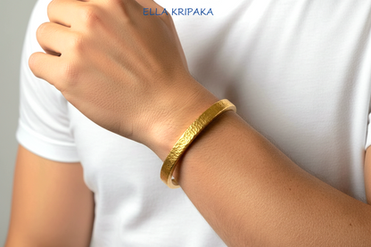 Hammered 24k 9999 gold bangle thick bracelet Ancient Rome style worn by a man on hand and on a white t-shirt background, artist-jeweler name 'Ella Kripaka' branding