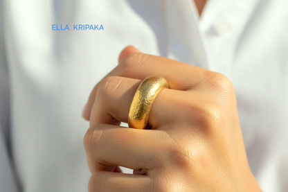 Hammered 24k Gold 9999 gold thick ring band with textured gold worn on model's finger and on a white blurred background, branded 'Ella Kripaka'