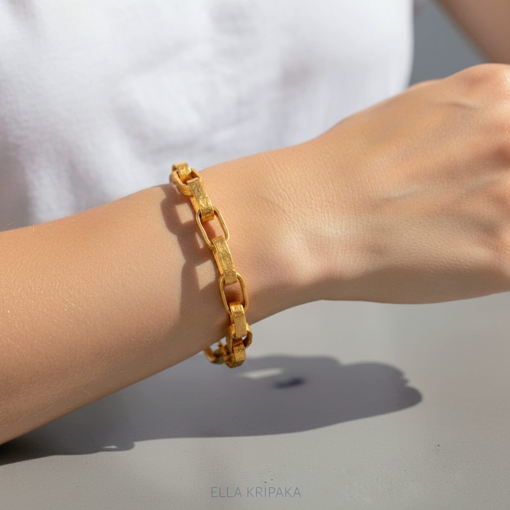 Hammered 24k 9999 gold organic bracelet chain with hammered uneven textures worn by a woman on wrist and on a neutral surface, artist name 'Ella Kripaka'