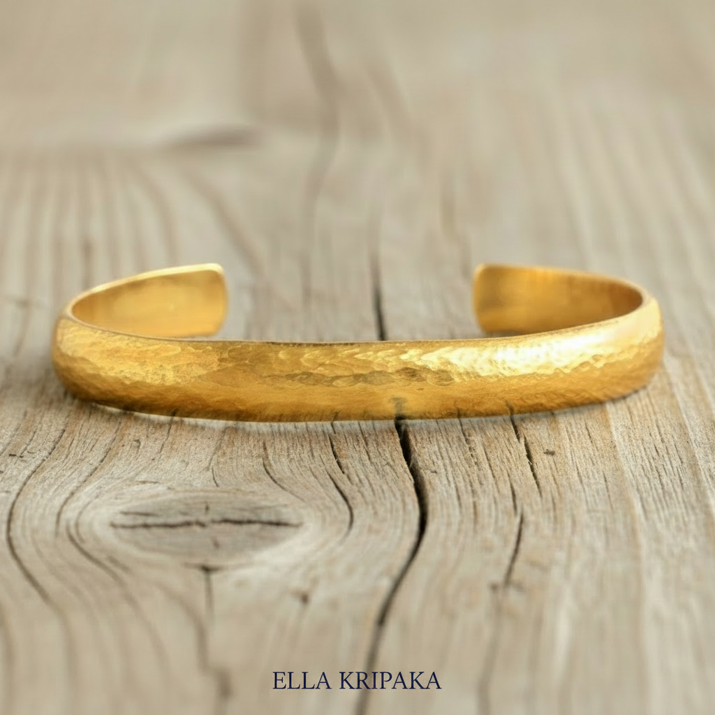 Hammered 24k gold bracelet cuff convex textured on a old light wooden background, branding artist 'Ella Kripaka'