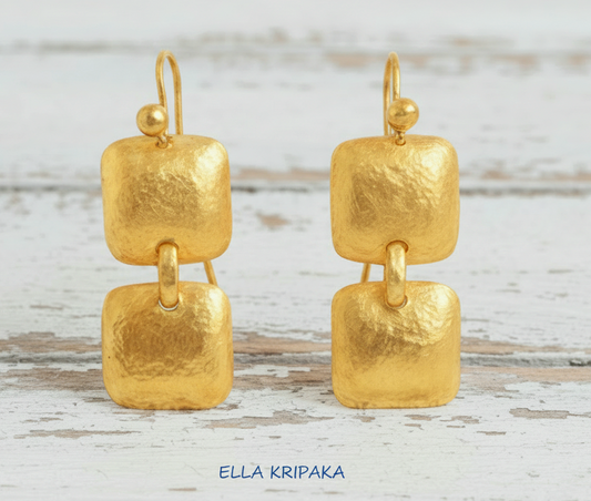 Solid 24k 9999 gold hammered Byzantine convex square earrings with hook clasps and shiny forged gold textures on old wooden background , artist's name 'ELLA KRIPAKA'