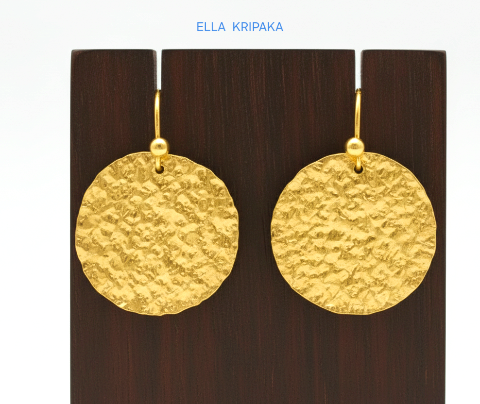 Organic 24k 9999 gold hammered disk earrings with  uneven edges are on dark wooden stand and on grey background, artist-jeweler's name 'Ella Kripaka'