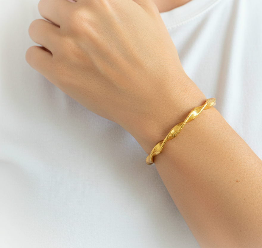 Twisted Viking hammered 24k 9999 gold bracelet cuff worn on wrist by person and on a white ombackground, branding artist-jeweler name 'Ella Kripaka'