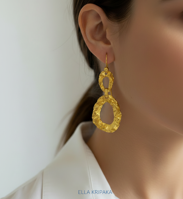 Organic hammered uneven 24k 9999 Gold earrings worn by a model on a white background , and with 'ELLA KRIPAKA' branding