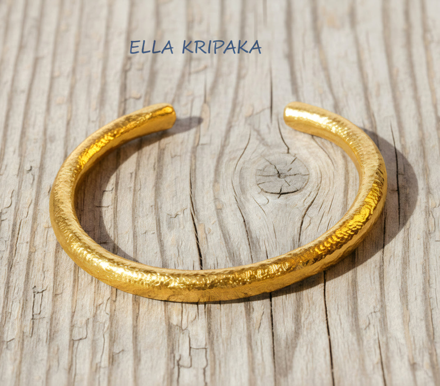 24k 9999 gold hammered Ancient Rome thick cuff bracelet on a grey old wooden surface, branded 'Ella Kripaka'