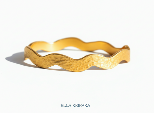 Hammered 24k 9999 Gold wavy bangle bracelet Ancient Egypt style on wooden surface, artist's name 'Ella Kripaka' branding