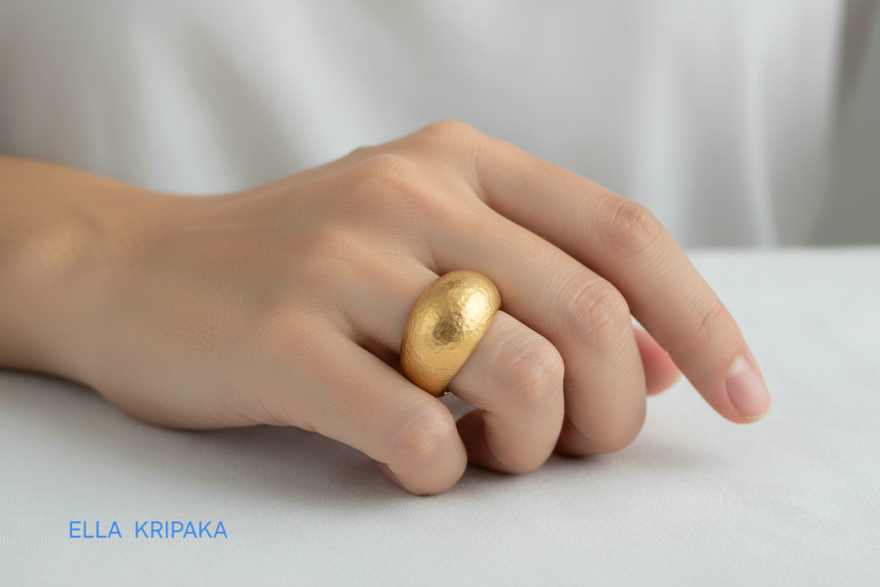 Hammered 24k 9999 Gold ring convex signet Ancient Rome style is worn by a person on finger and on plain background, artist-jeweler's name 'Ella Kripaka' branding