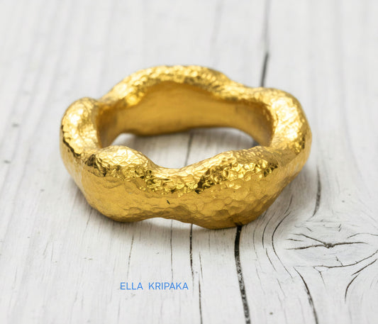 Hammered 24k 9999 Gold thick uneven wavy ring organic with textured gold on a white old wooden background, branded 'Ella Kripaka'