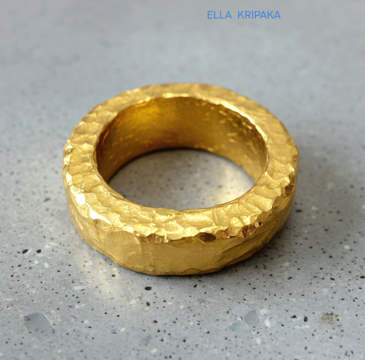 Hammered 24k 9999 Gold thick uneven ring organic with a textured gold surface on a grey concrete background, branded 'Ella Kripaka'