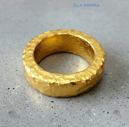Hammered 24k 9999 Gold thick uneven ring organic with a textured gold surface on a grey concrete background, branded 'Ella Kripaka'