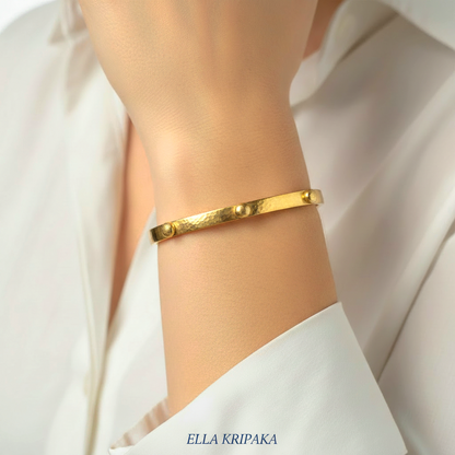 24k gold hammered cuff textured bracelet with convex rounds is worn by a woman on wrist and on white shirt background, artist 'Ella Kripaka' branding
