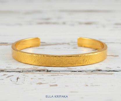 Hammered 24k 9999 gold cuff thick bracelet Ancient Rome style on old white wooden background, artist-jeweler's name 'Ella Kripaka'