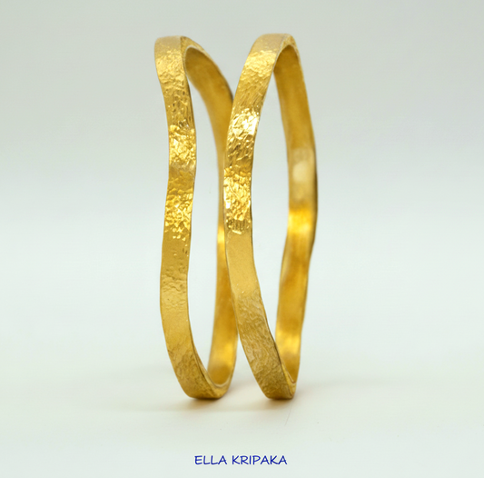 Uneven hammered 24k 9999 Gold organic two bangles bracelets on white surface, artist's name 'Ella Kripaka' branding